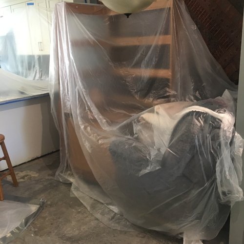Covered furniture and exposed wall framing during water damage rebuild