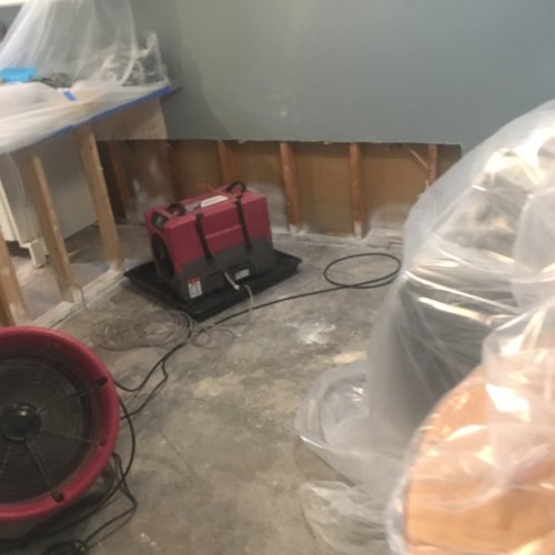 Exposed lower wall framing and bare floor during water damage repairs