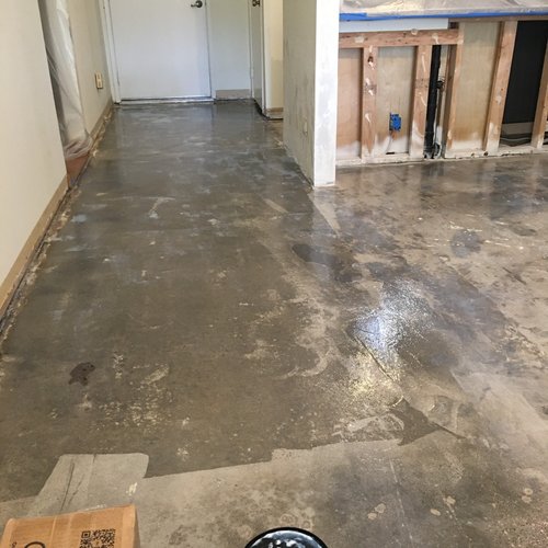 Bare kitchen and hallway floor during water damage rebuild preparation